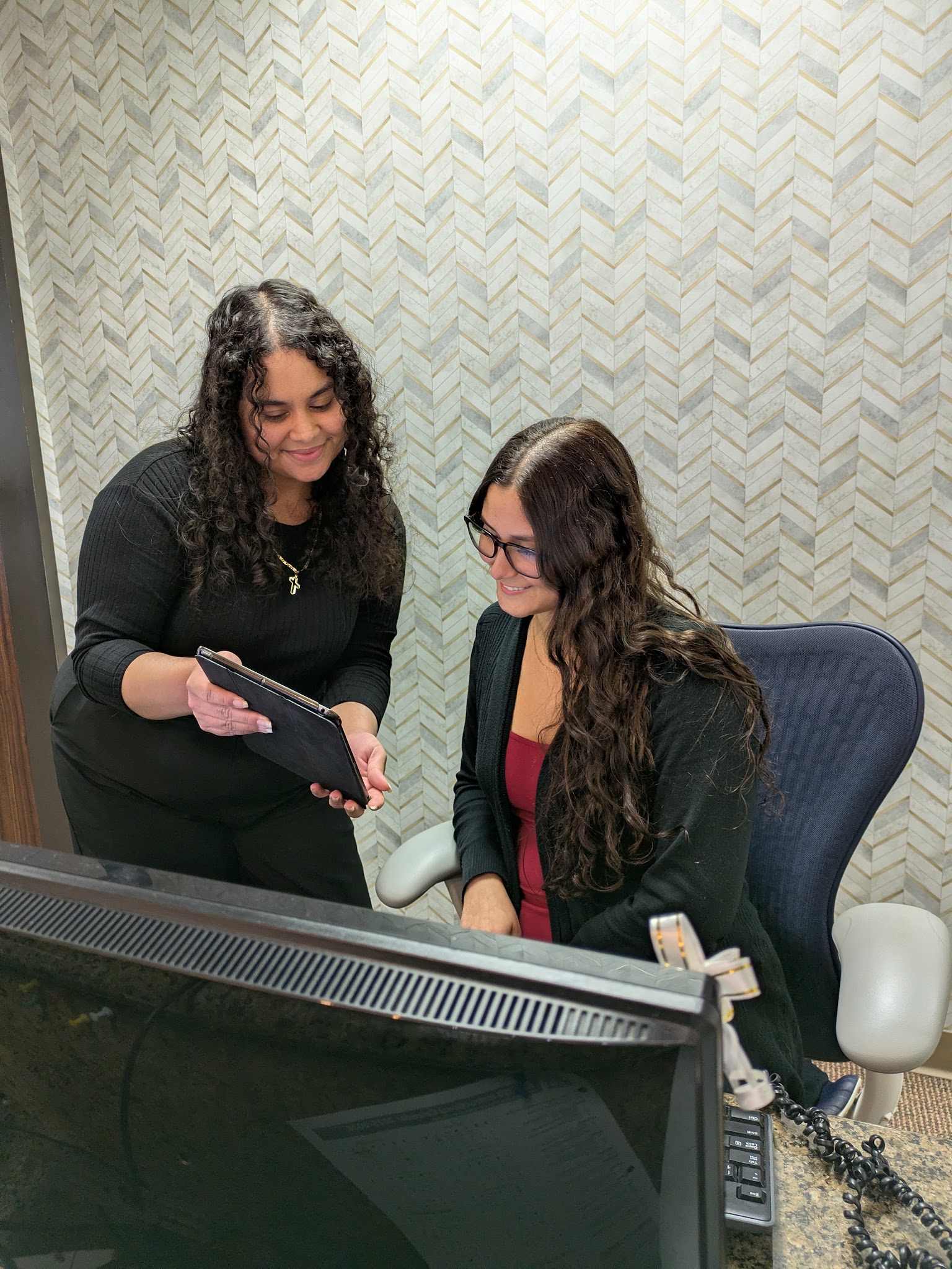 Two of the front desk going through a plan on the tablet