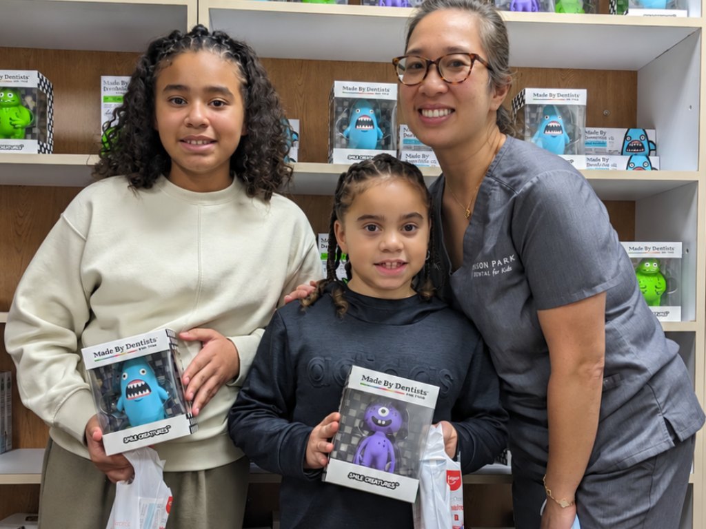 Two young patients with their prizes and a smiling team member