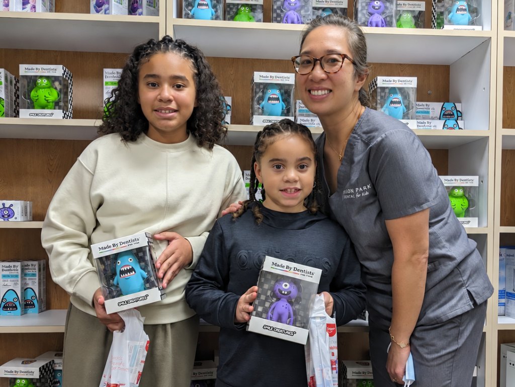 Dr. Tam Nguyen with two young patients holding their new toys in the kids practice