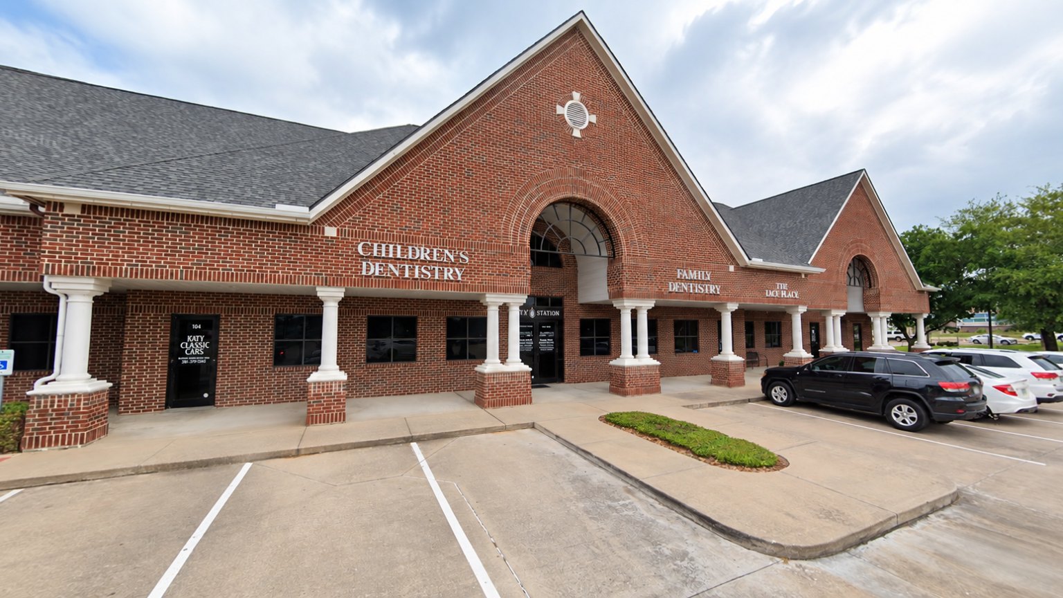 The brick building that holds both practices, with its arched entrance and parking in front