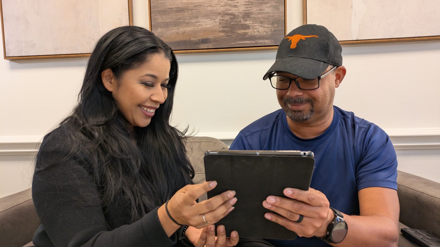 A coordinator going over a treatment plan on a tablet with a patient on the sofa