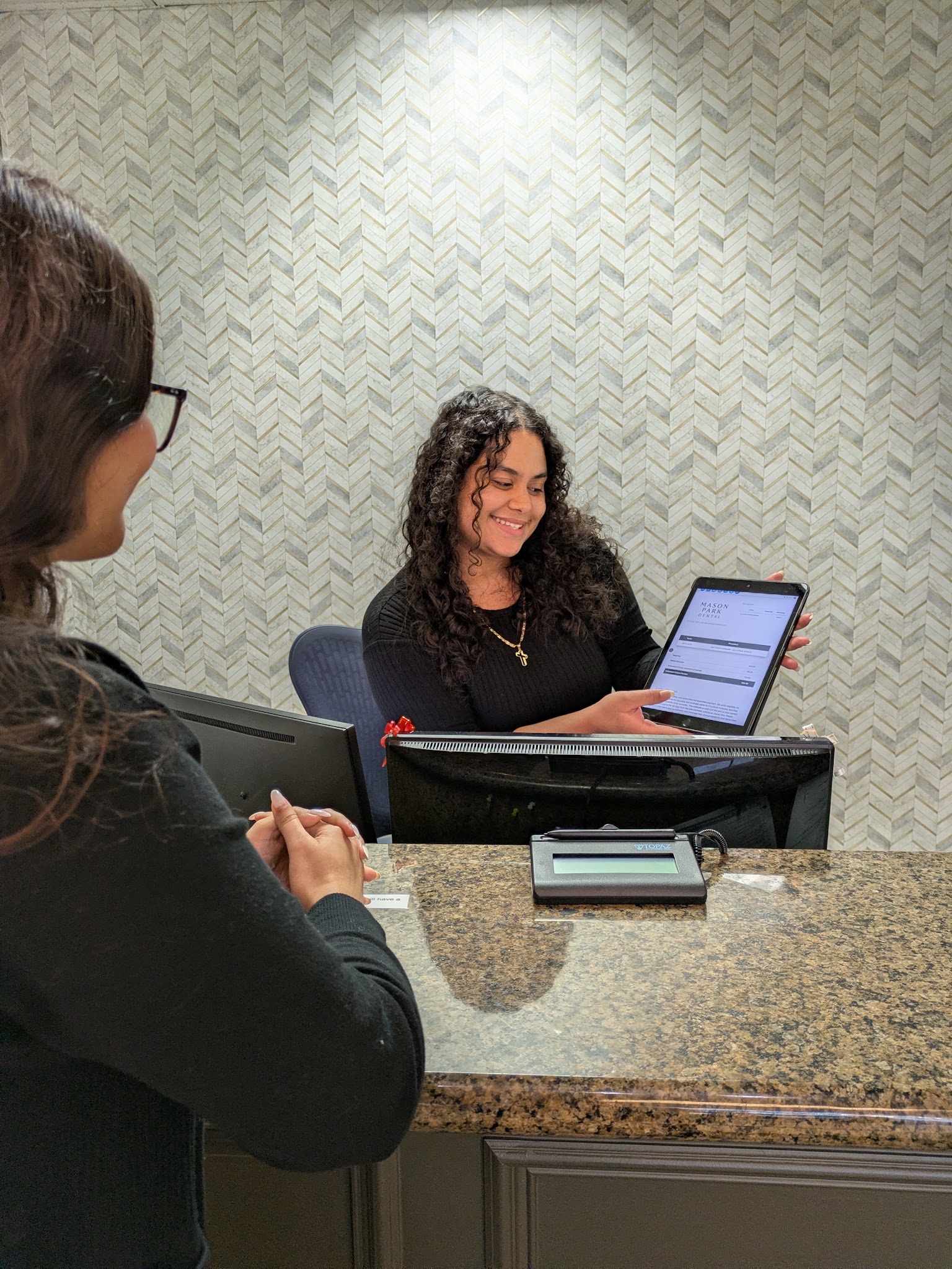 The front desk turning the tablet so the patient can see the plan