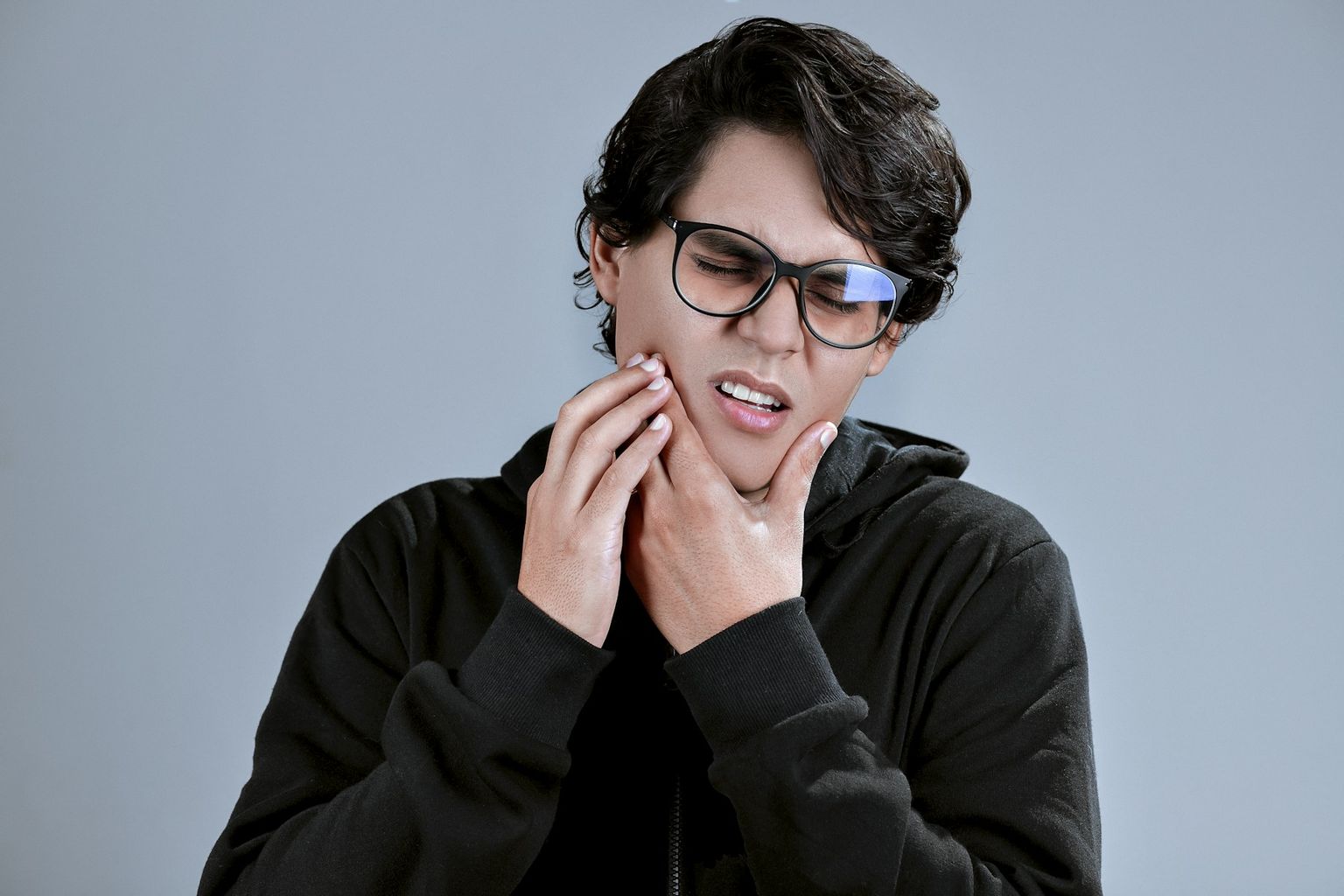 A woman holding the side of her jaw