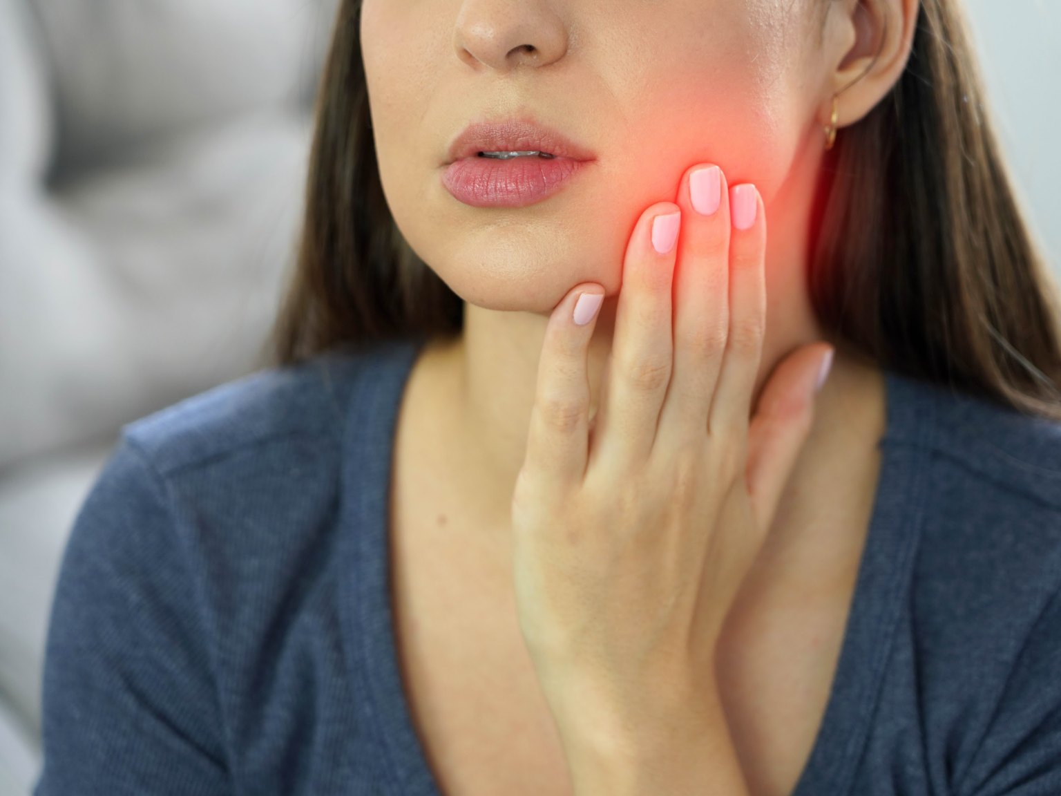 A woman holding her jaw, a red glow marking the sore spot