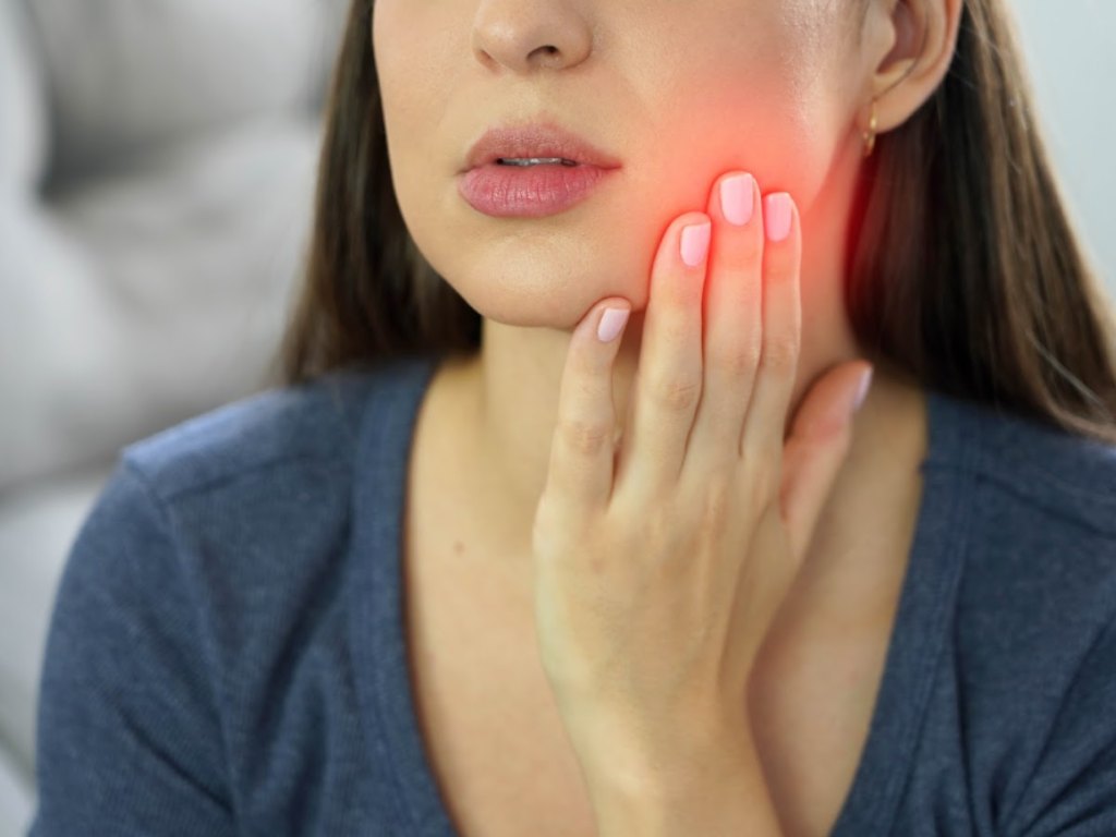 A woman holding her jaw, the sore side marked