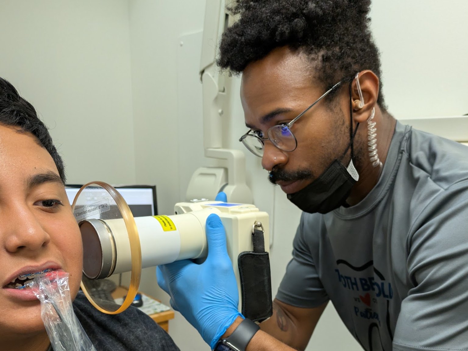 A team member taking a handheld x-ray of a teenager with braces